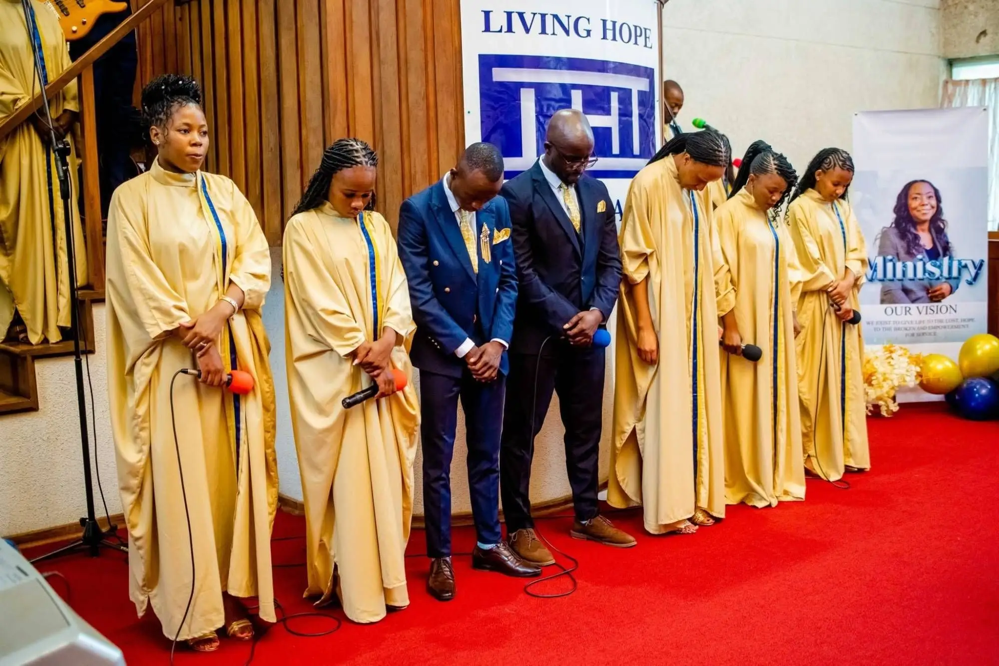 Choir members and ministers standing with heads bowed in prayer